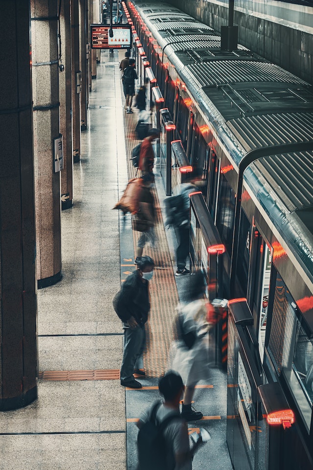 Commuters with monthly train tickets boarding a train waiting by the platform