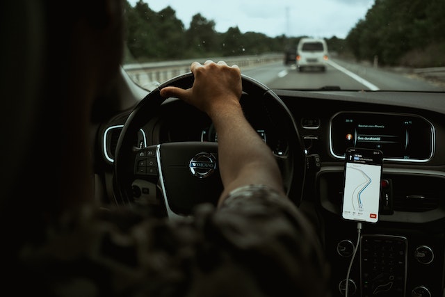Image: A man driving a car and using the navigation on a smartphone attached to a car phone holder A man driving a car and using the navigation on a smartphone attached to a car phone holder