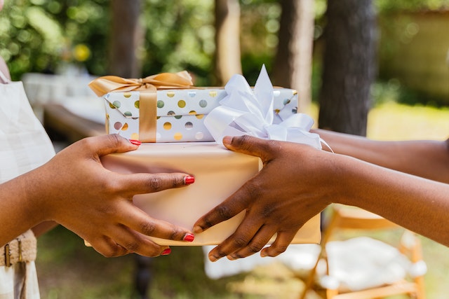 Gifts for your friends: A woman handing over wrapped gift boxes to a friend