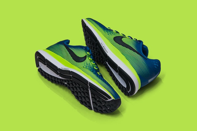 A pair of blue and green fashion Nike running shoes for men on a green background