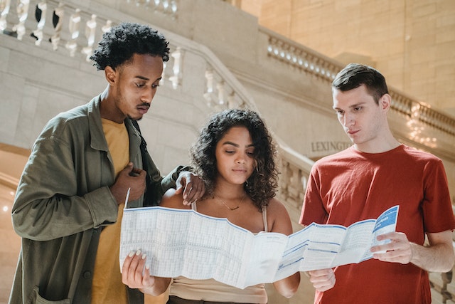 How to travel as a student: a group of three students looking at a map together