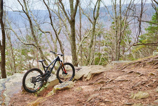 A black mountain bicycle parked against some rocks on a mountaintop