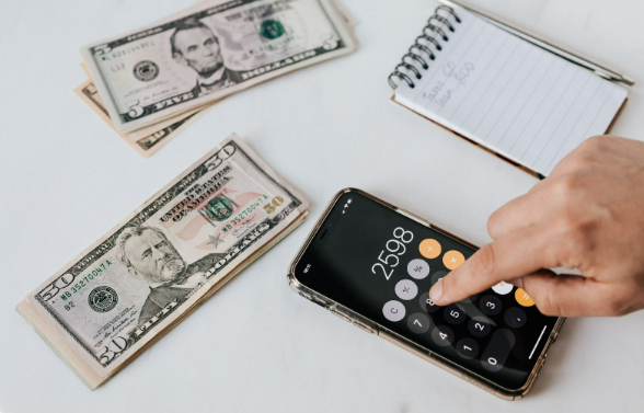 Saving on food: A person calculating how much money to budget on food using a mobile calculator.