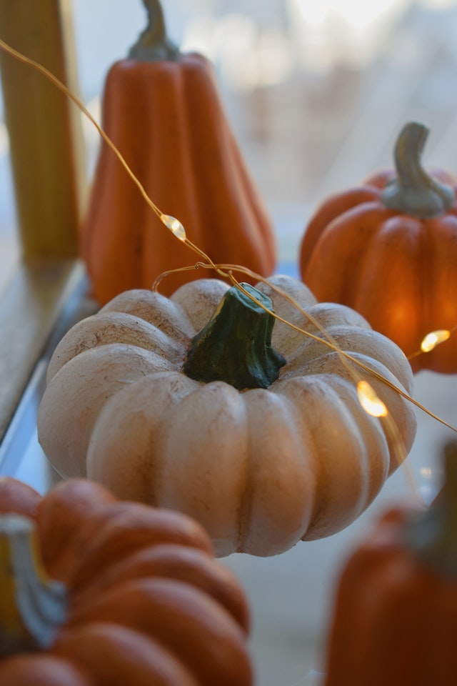 Spooky home decor: Four pumpkins sitting on a glass table covered in string lights