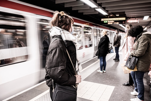 A crowd of people waiting for a train to stop while wondering how to get cheap train tickets