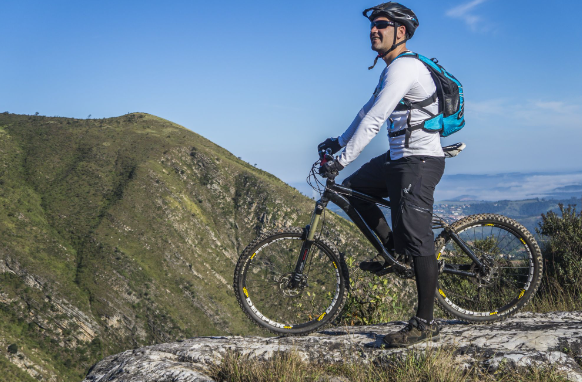 Image: A man standing on a mountain with his electric mountain bike. A man standing on a mountain with his electric mountain bike.