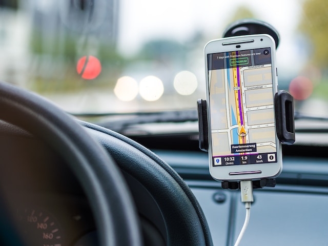 Image: A person driving while using a phone holder for the car to use the maps navigation A person driving while using a phone holder for the car to use the maps navigation
