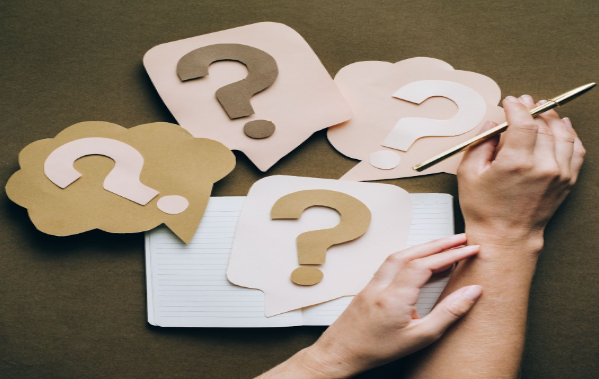 Image: Question marks made with paper crafts on desk, with a person asking questions about the combi boiler challenge. Question marks made with paper crafts on desk, with a person asking questions about the combi boiler challenge.