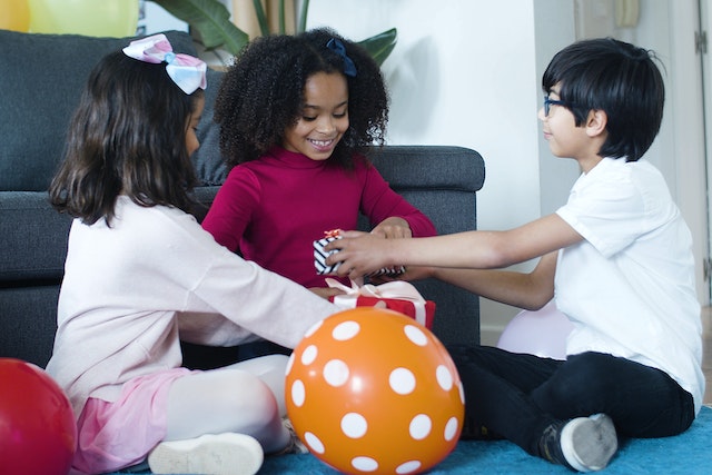 Children sitting on the floor while holding personalised gifts for friends