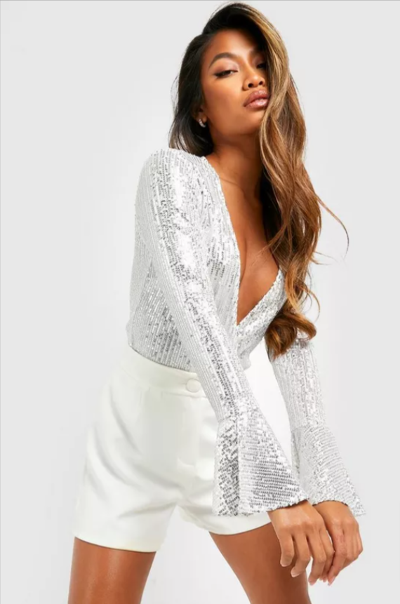 A model posing in a silver sequined wrap body suit and white cashmere shorts