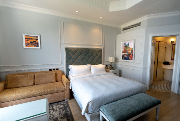 Image: A brown single sofa bed in the bedroom & is placed next to a double bed. A brown single sofa bed in the bedroom & is placed next to a double bed.