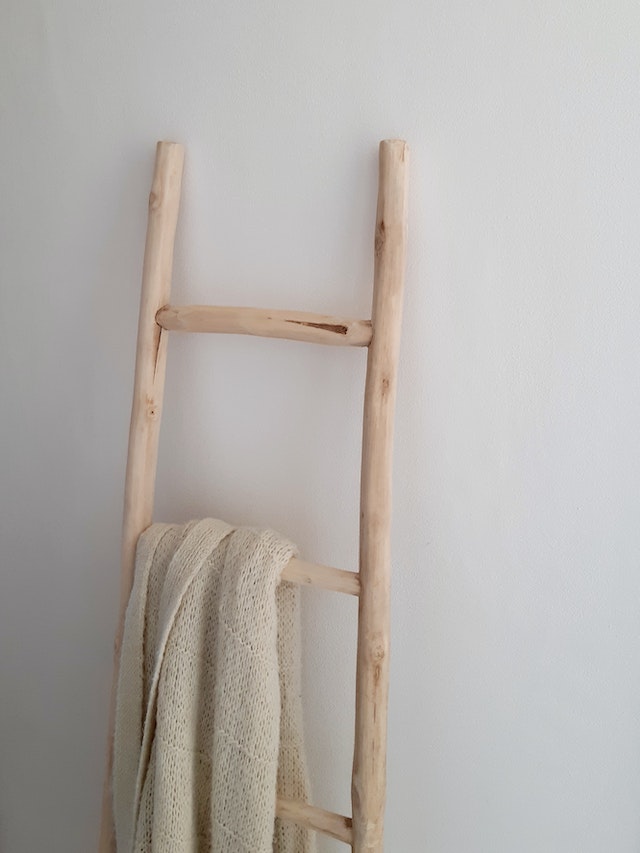 An idea for small bathroom storage: a wooden towel ladder leaning against a wall
