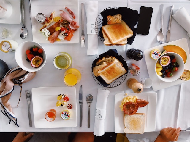 A table set for the brunch club with different size plates and a variety of food.