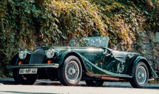 One of the dark green eBay kit cars is displayed on the road.