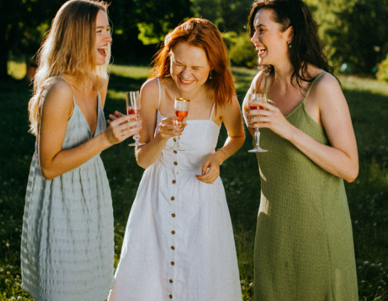 Three women wearing Monsoon party dresses at a garden party