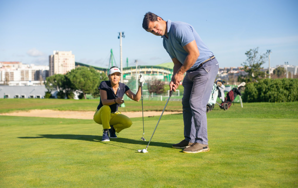 Man standing with a putter and golf ball with a woman sitting behind him, discovering which are the best golf balls for beginners.