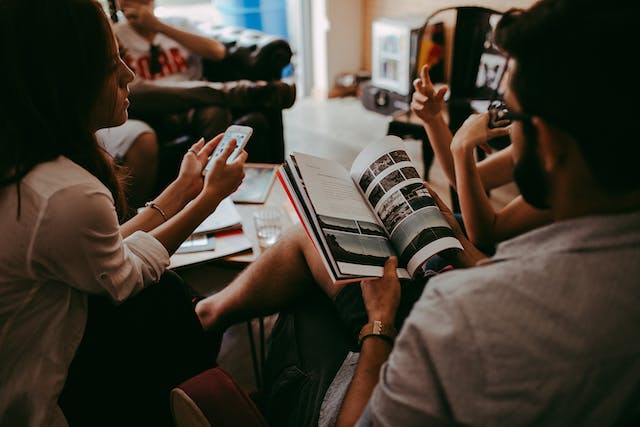 Books for World Book Day: People in a social setting with one going through a book and the other holding a phone.