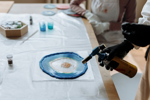 What is resin art: A pair of artists popping bubbles in a resin casting with a blow torch