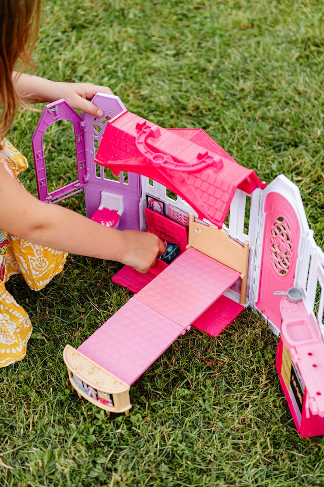 Barbie's dream house on display with a little girl playing with it.
