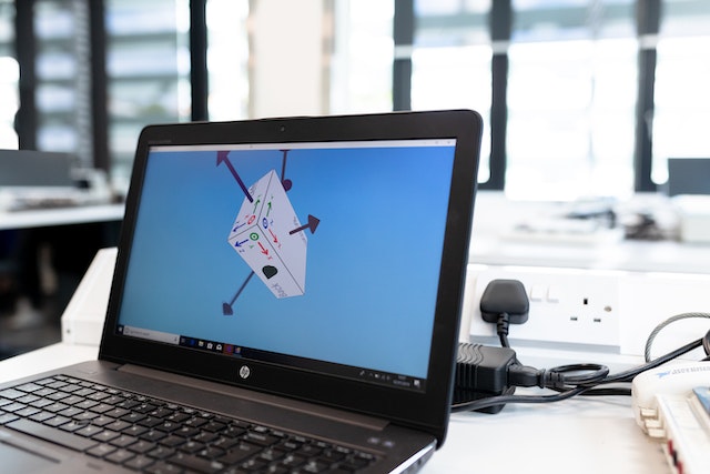 A black HP touch screen laptop on a table with a geometric image on the screen