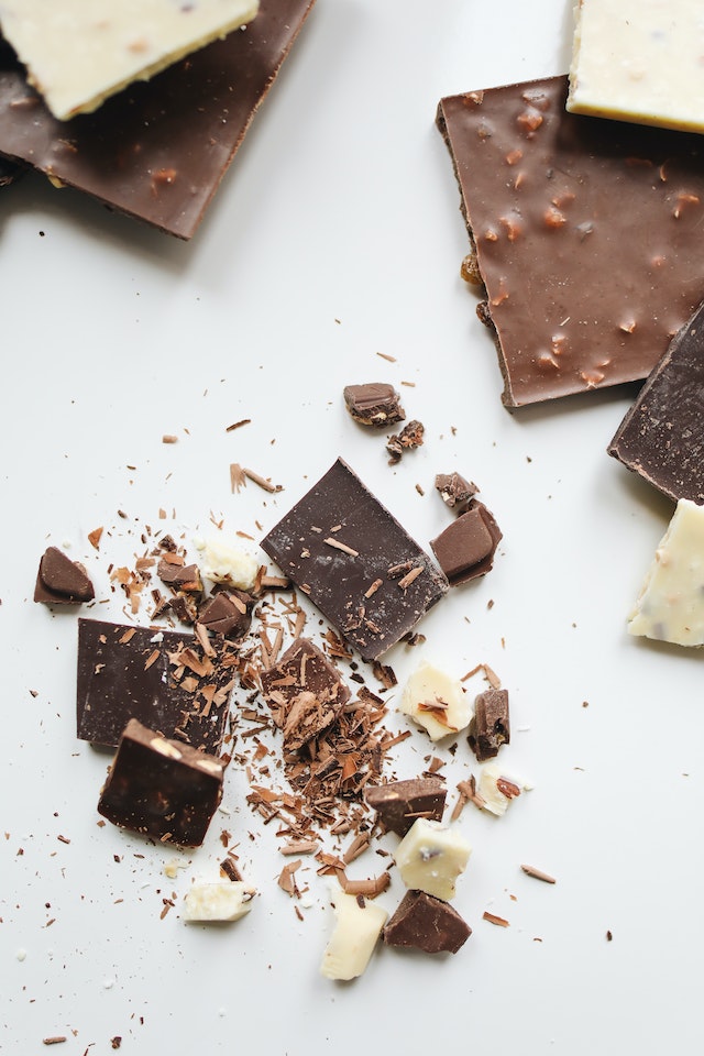 Broken up pieces of chocolate laying on a surface as someone learns how to make chocolate