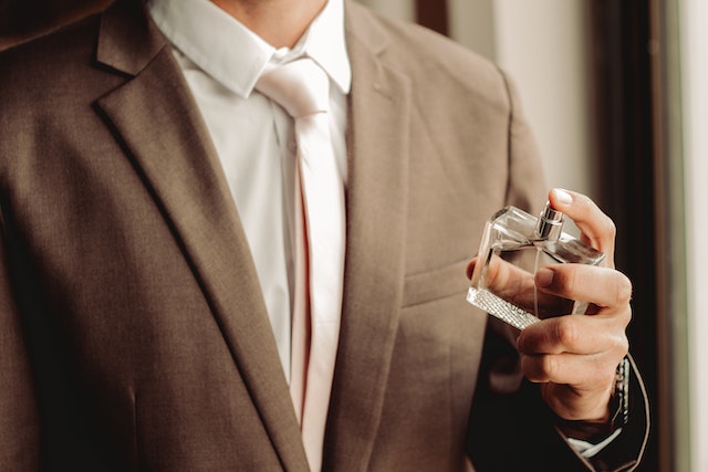 Image: A man in a suit spraying a bottle of fragrance on himself for Father’s Day 2023 A man in a suit spraying a bottle of fragrance on himself for Father’s Day 2023