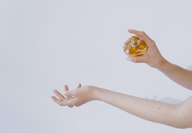 A person spraying a bottle of fragrance on their wrist to test eau de toilette vs eau de parfum