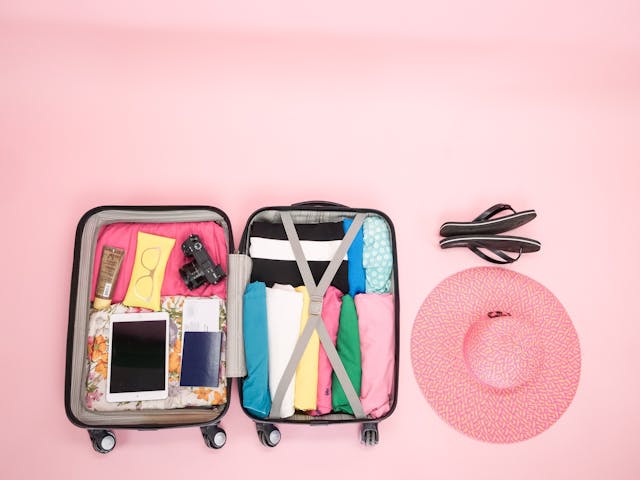 Image: A summer holiday capsule wardrobe and gadgets packed into an open suitcase A summer holiday capsule wardrobe and gadgets packed into an open suitcase