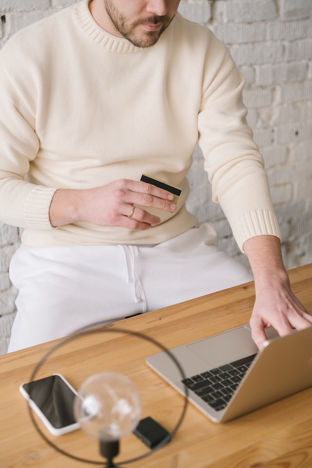 Amex platinum card: A man sitting at a desk with a laptop, phone and credit card