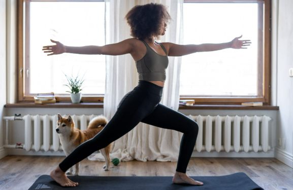 A woman doing yoga exercises in her home with her new Mirafit home gym set