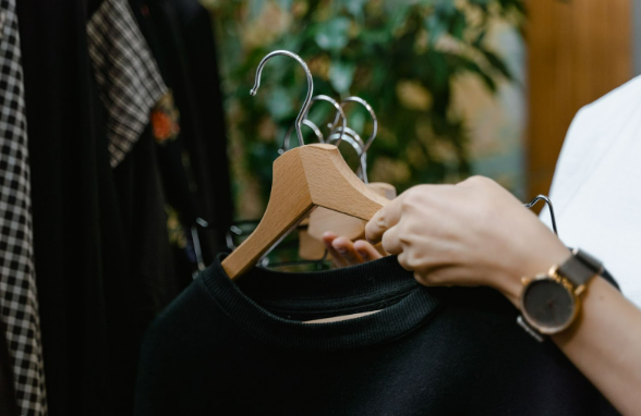 A man holding clothes on hangers in a men’s clothing store.