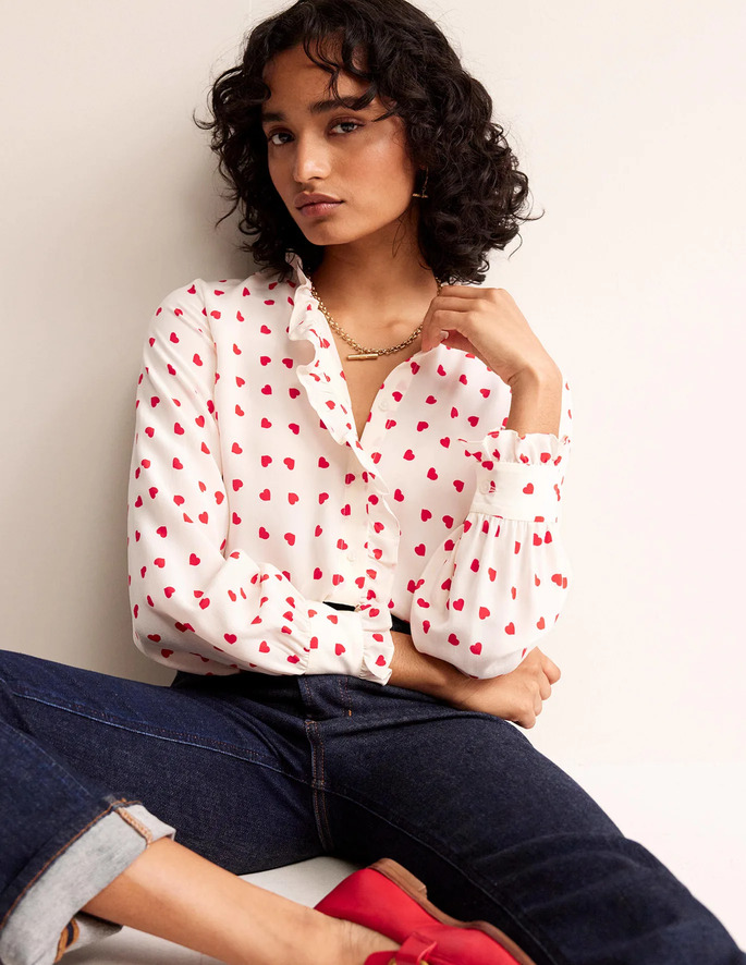 what to wear on Valentine's Day: A model posing in a white blouse and blue jeans