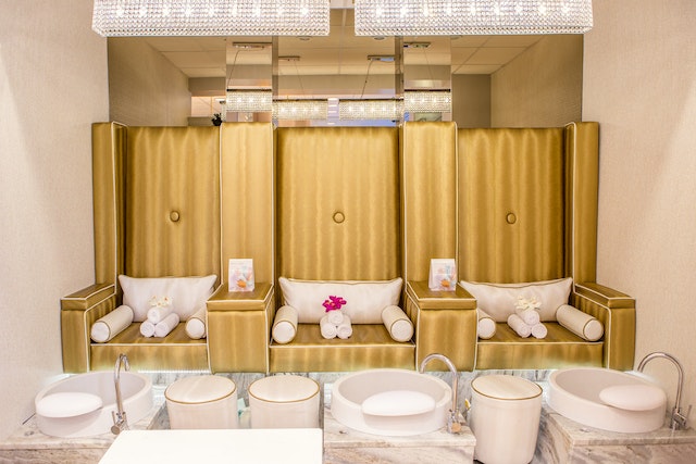 Three brown chairs with white pillows and white towels and three white basins for spa treatments for Mother’s Day gifts