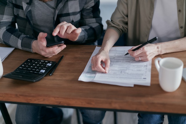A man and woman going over their budget with papers and a calculator during no spend month