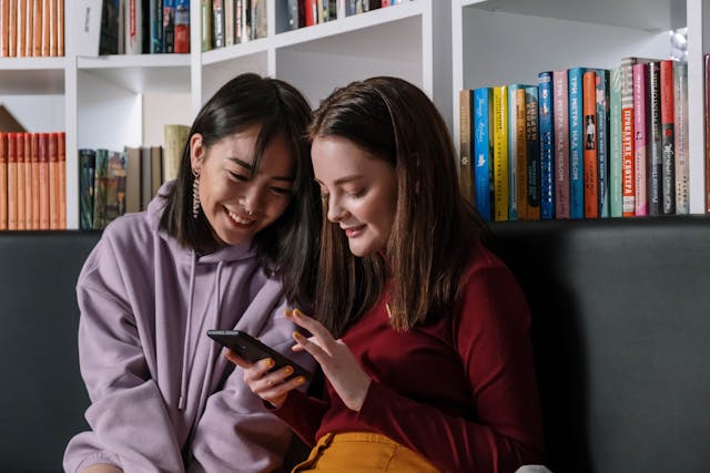Red Nose Day ideas for schools: two girls smiling while scrolling on a phone