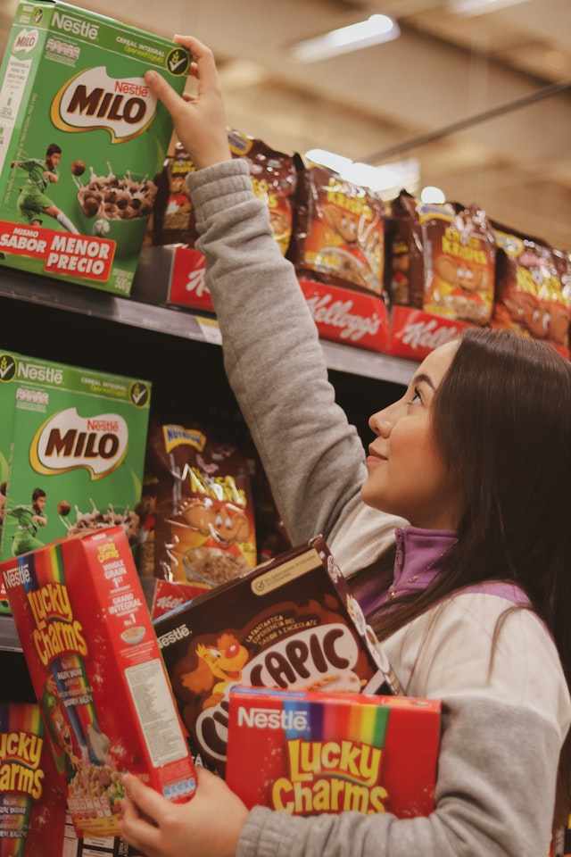 own-label products: A woman reaching for a box of cereal with three more boxes in her arms