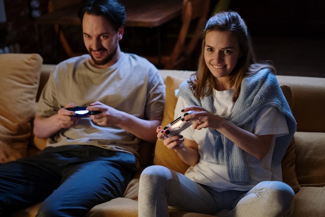 A couple playing cheap Nintendo Switch games together on a beige couch