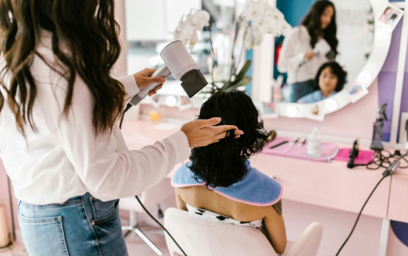 Image: A hairdresser using dry hair styling products on her client's hair. A hairdresser using dry hair styling products on her client's hair.