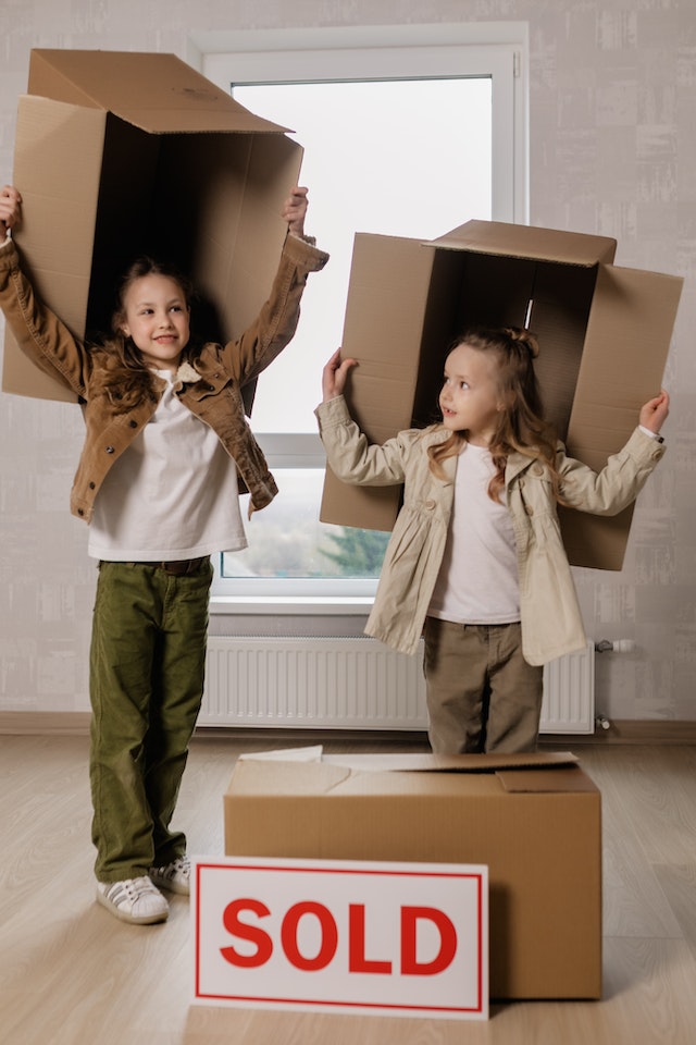 Best property websites: Two children holding boxes over their heads in front of a ‘sold’ sign