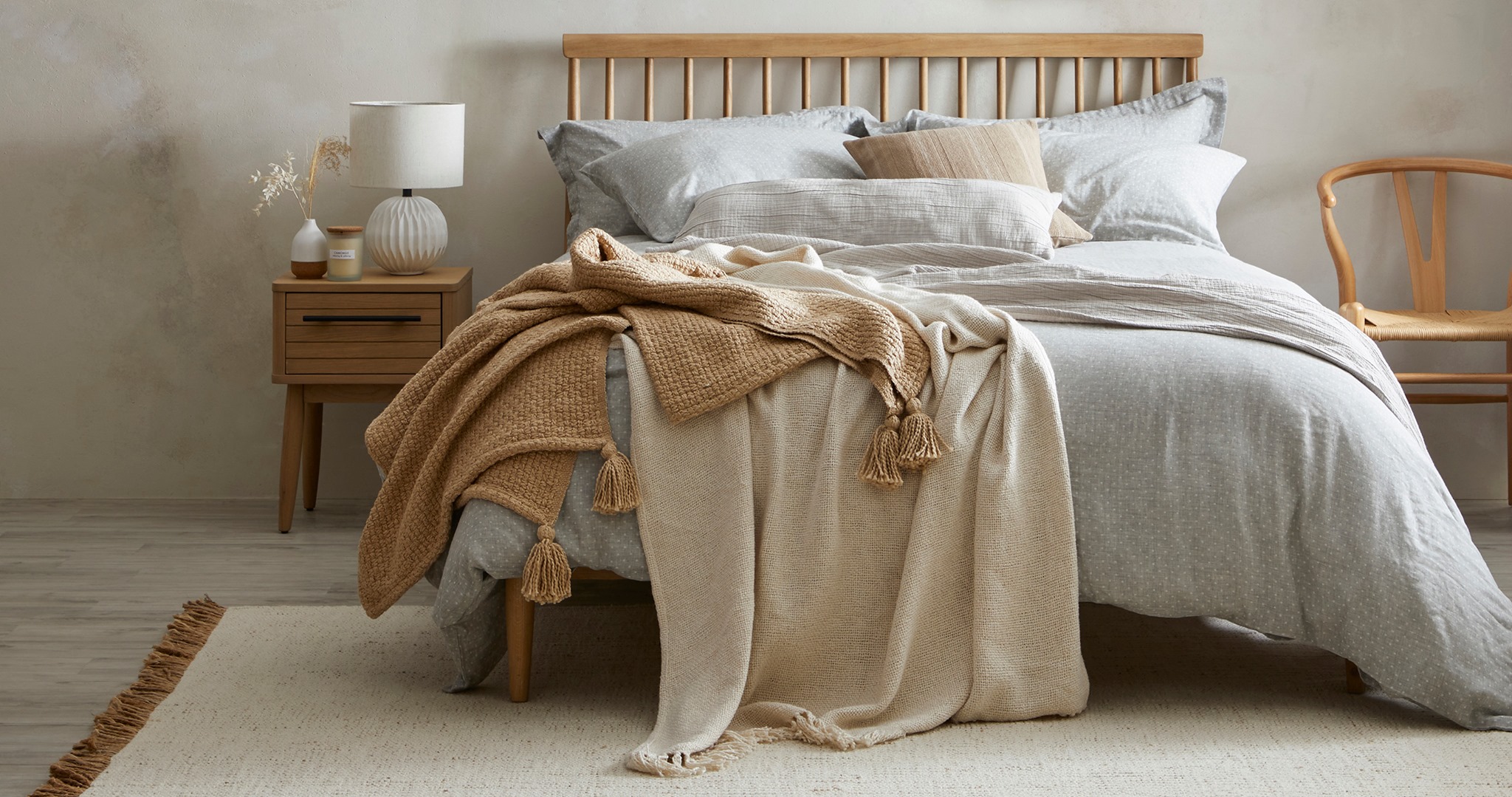 A bed covered in beige, brown and grey blankets, duvet and Dunelm memory foam pillows