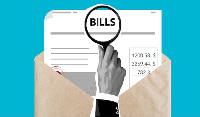 energy saving tips for winter: A hand with a magnifying glass hovering over an envelope of bills
