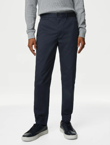 A man wearing navy chino pants and black sneakers from Marks & Spencer