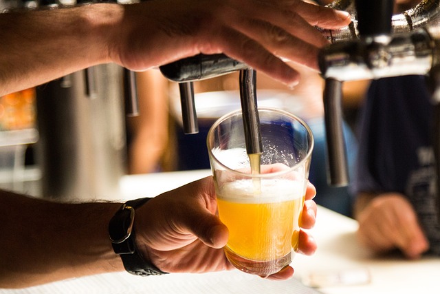 A hand pouring beer from an alcohol dispenser with a blurry background