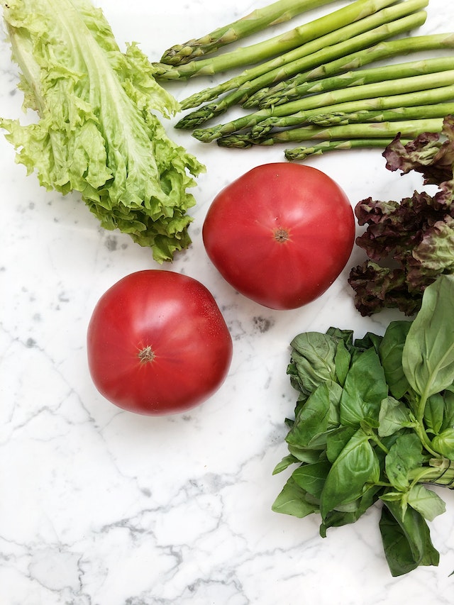 A pack of wonky fruit and veg scattered across a white marble countertop