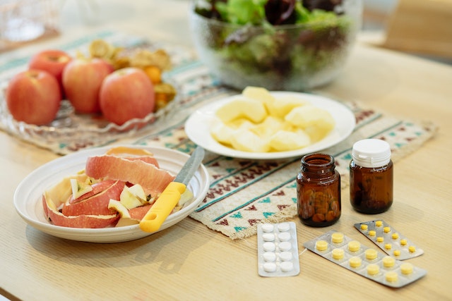 Image: A salad and apples next to supplements on a table for a balanced diet to manage stress A salad and apples next to supplements on a table for a balanced diet to manage stress