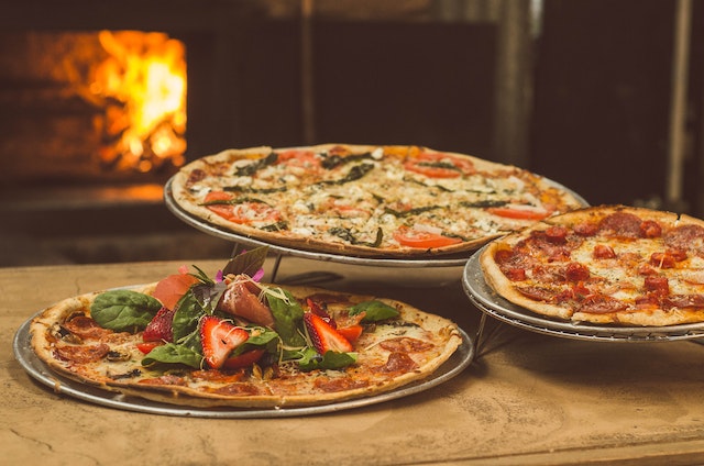 Best restaurants on Tastecard: Three pizzas on plates seated in front of a pizza oven