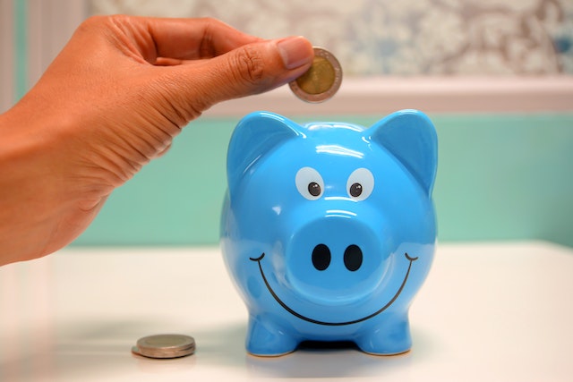 A person putting one of three coins in a blue piggy bank during no spend days