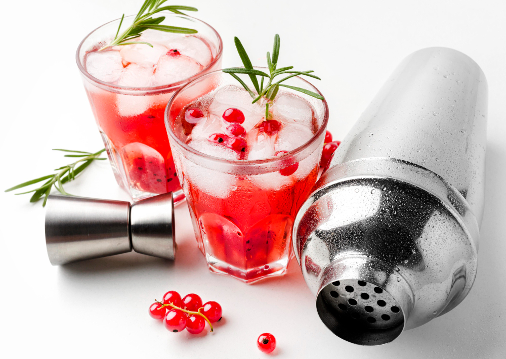 Prosecco Cocktails With Vodka: Two glasses of cranberry vodka cocktail with shakers and cranberries on the side.