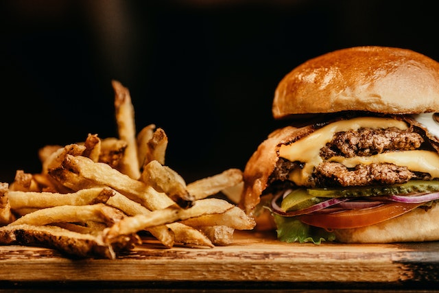 Where can I use my Tastecard: A burger and chips seated on a wood board on a black background