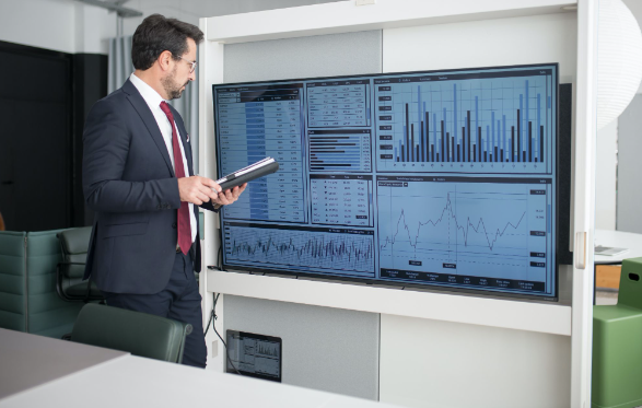 Man holding notepad and looking at ways to save with graphs on a screen for his mortgage saver account.